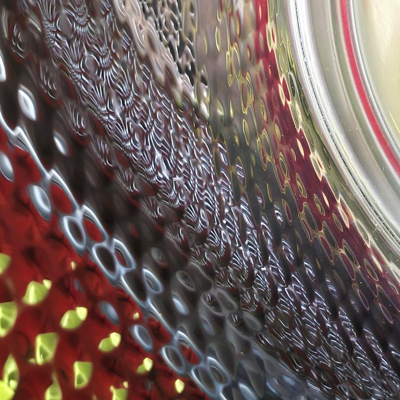Groene en rode reflecties in de trommel van een wasmachine uit het hoofdstuk Inner Weave